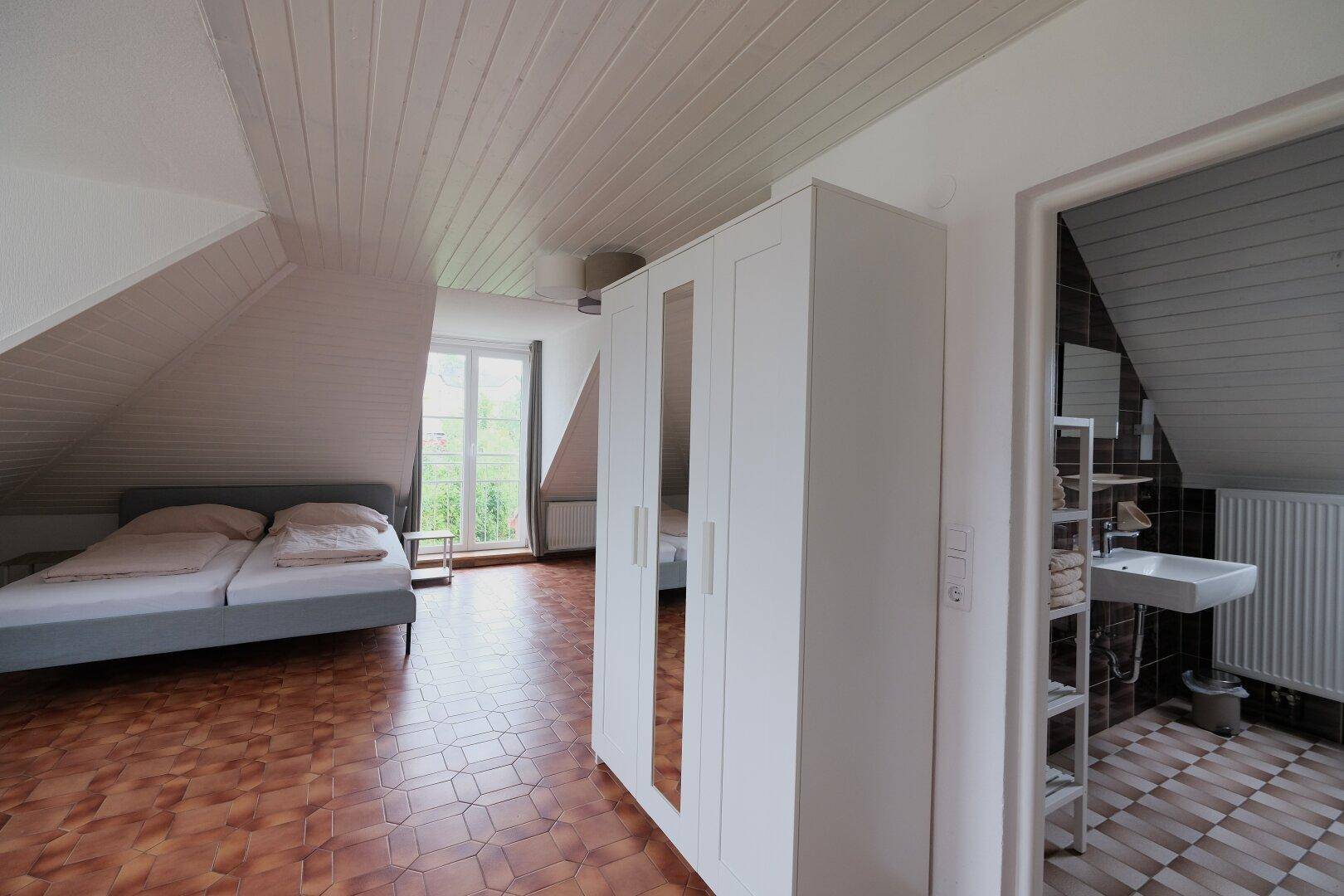 Dachgeschoss-Schlafzimmer mit Zugang zu einem Badezimmer und schrägen Wänden.