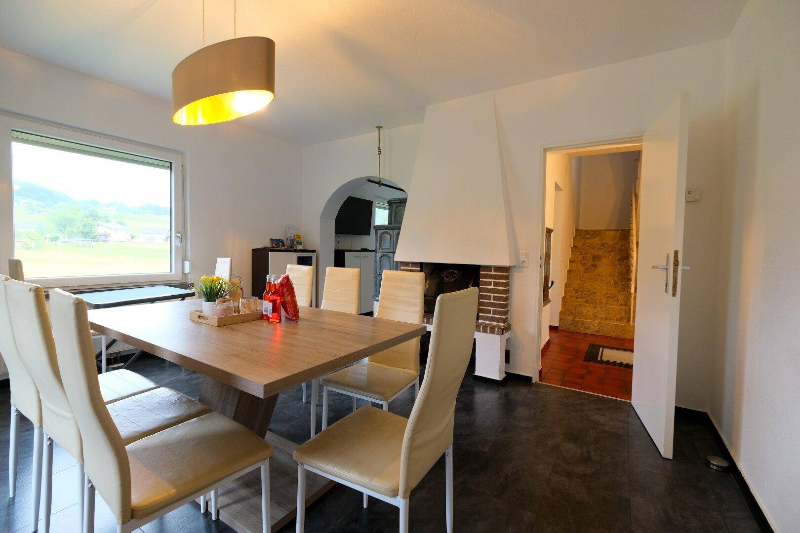Esszimmer mit Holztisch, Kamin und Zugang zum Flur, ideal für gesellige Runden.