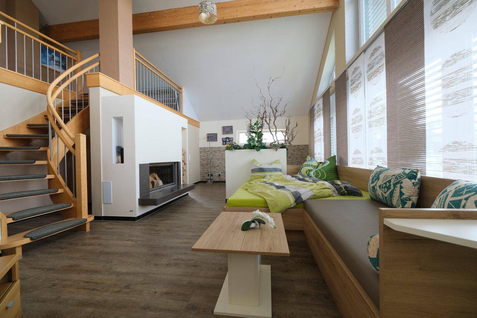 Heller Wohnbereich mit Kamin, Wendeltreppe und gemütlicher Sitzecke mit Tagesbett.