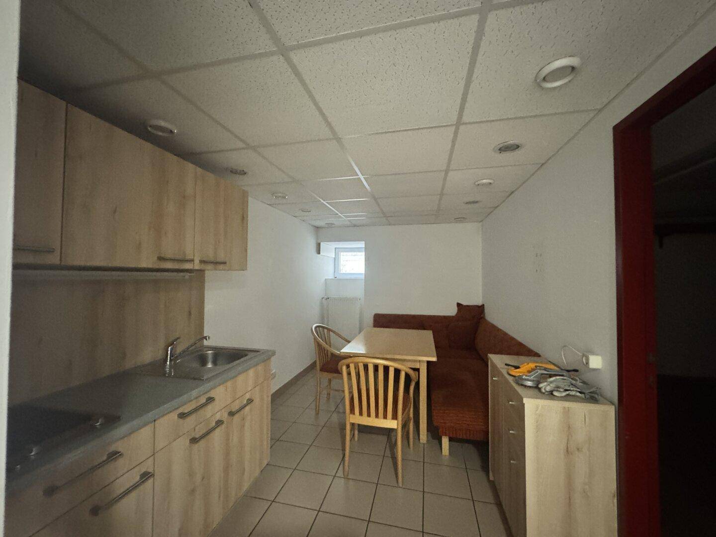 Kleine Küchenzeile mit hellem Holz und Essbereich, ausgestattet mit Tisch und Sitzbank, ideal für Pausen.