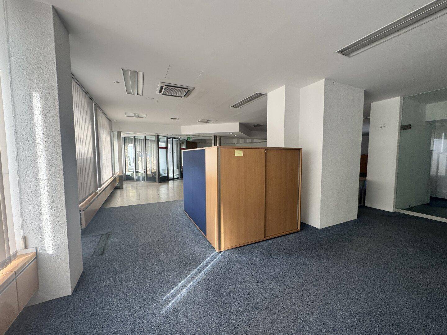 Heller Bürobereich mit Teppichboden und mobilen Trennwänden, die flexible Arbeitsbereiche ermöglichen und viel Licht hereinlassen.