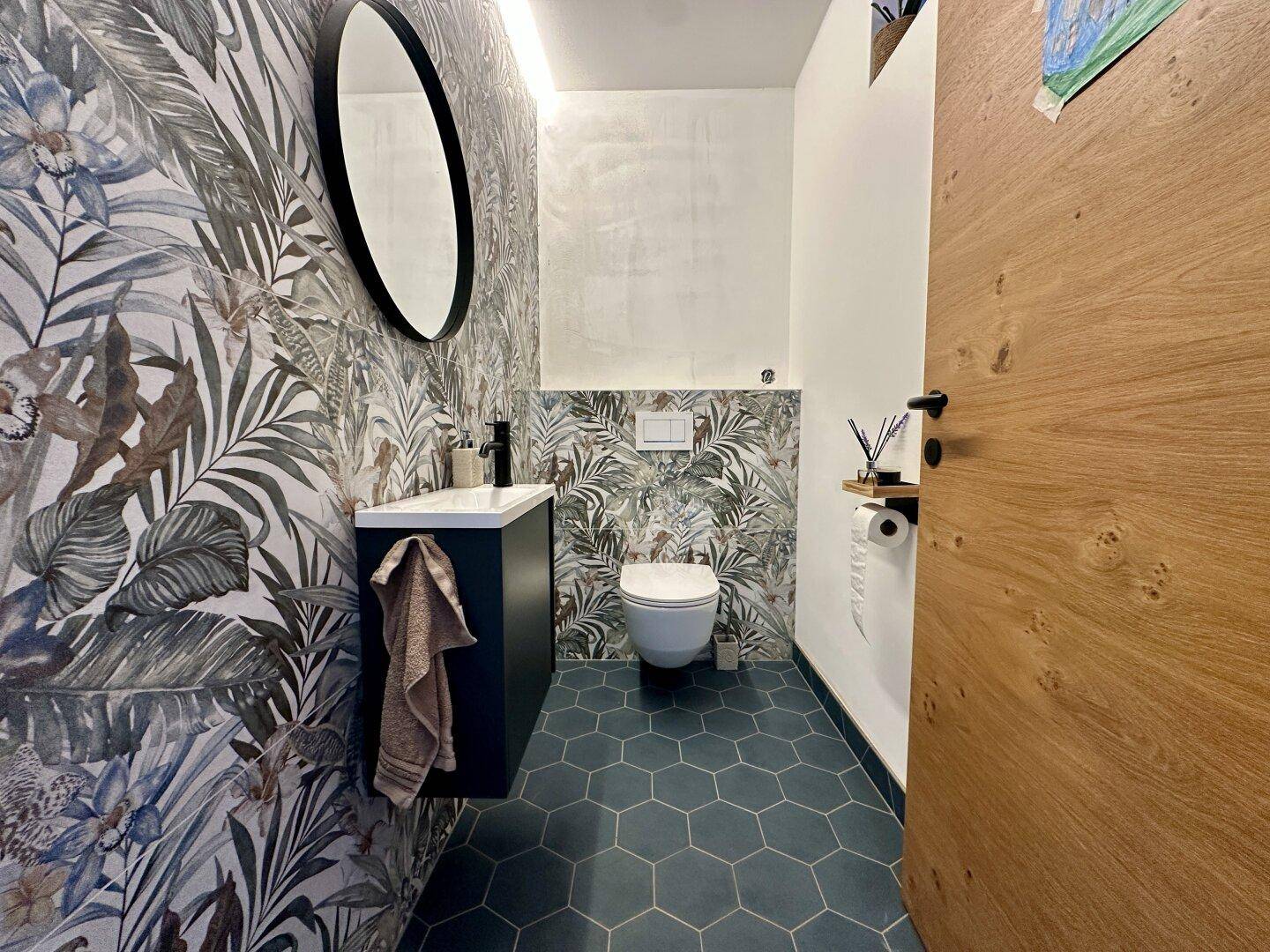 Modernes Gäste-WC mit auffälliger Dschungel-Tapete und sechseckigen Bodenfliesen.