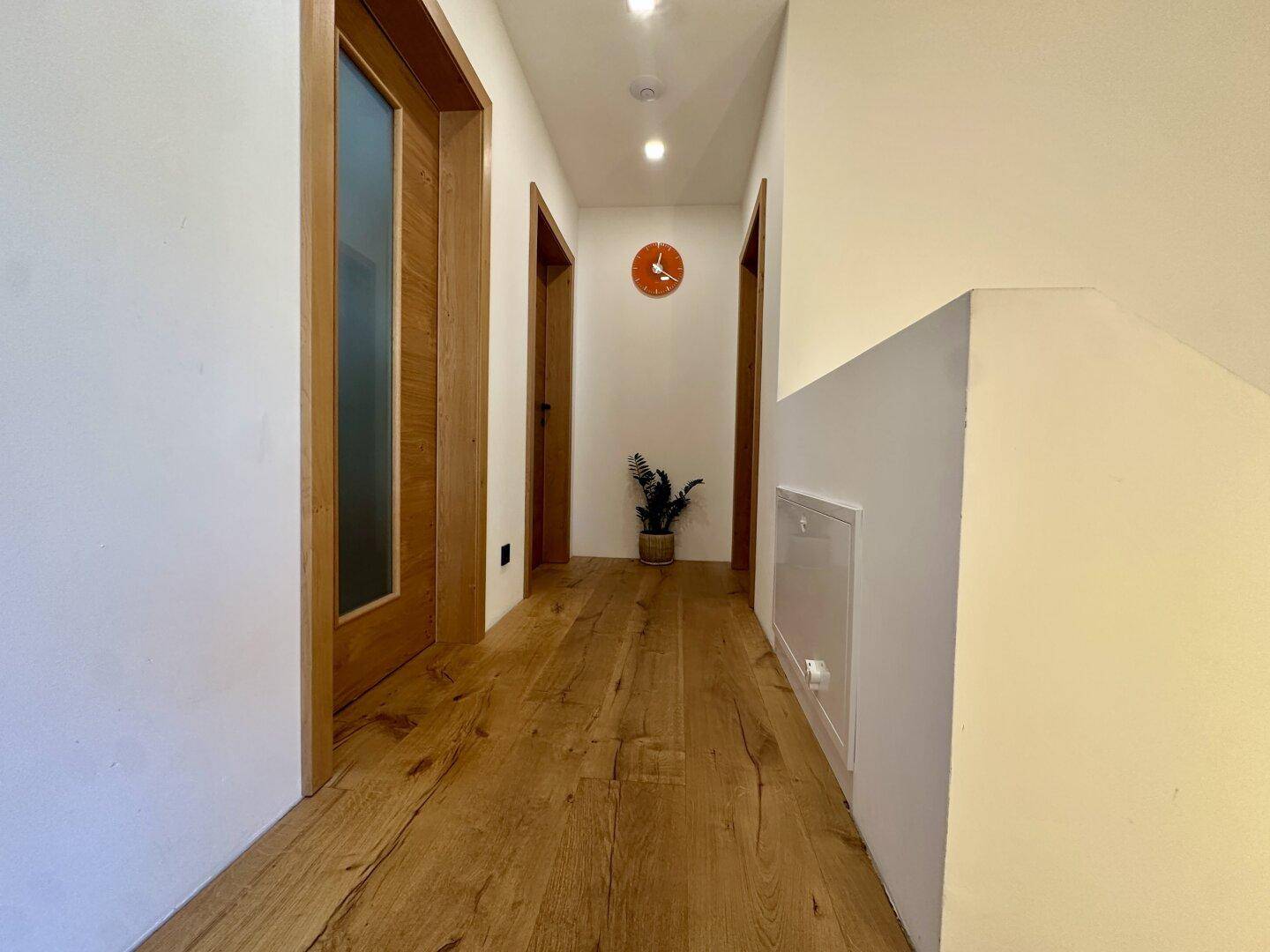Heller Flur mit Holzboden und mehreren Türen, die zu den Zimmern führen.