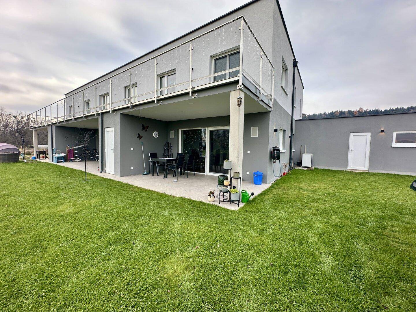 Hinterhof mit Rasenfläche, gepflasterter Terrasse und Blick auf die umliegende Landschaft.