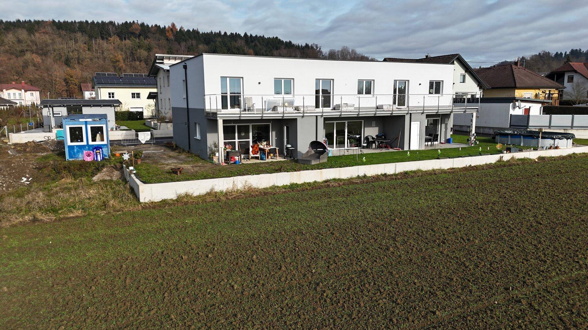 Rückansicht eines modernen Reihenhauses mit Terrassen, Balkonen und einem Aufstellpool im Garten.