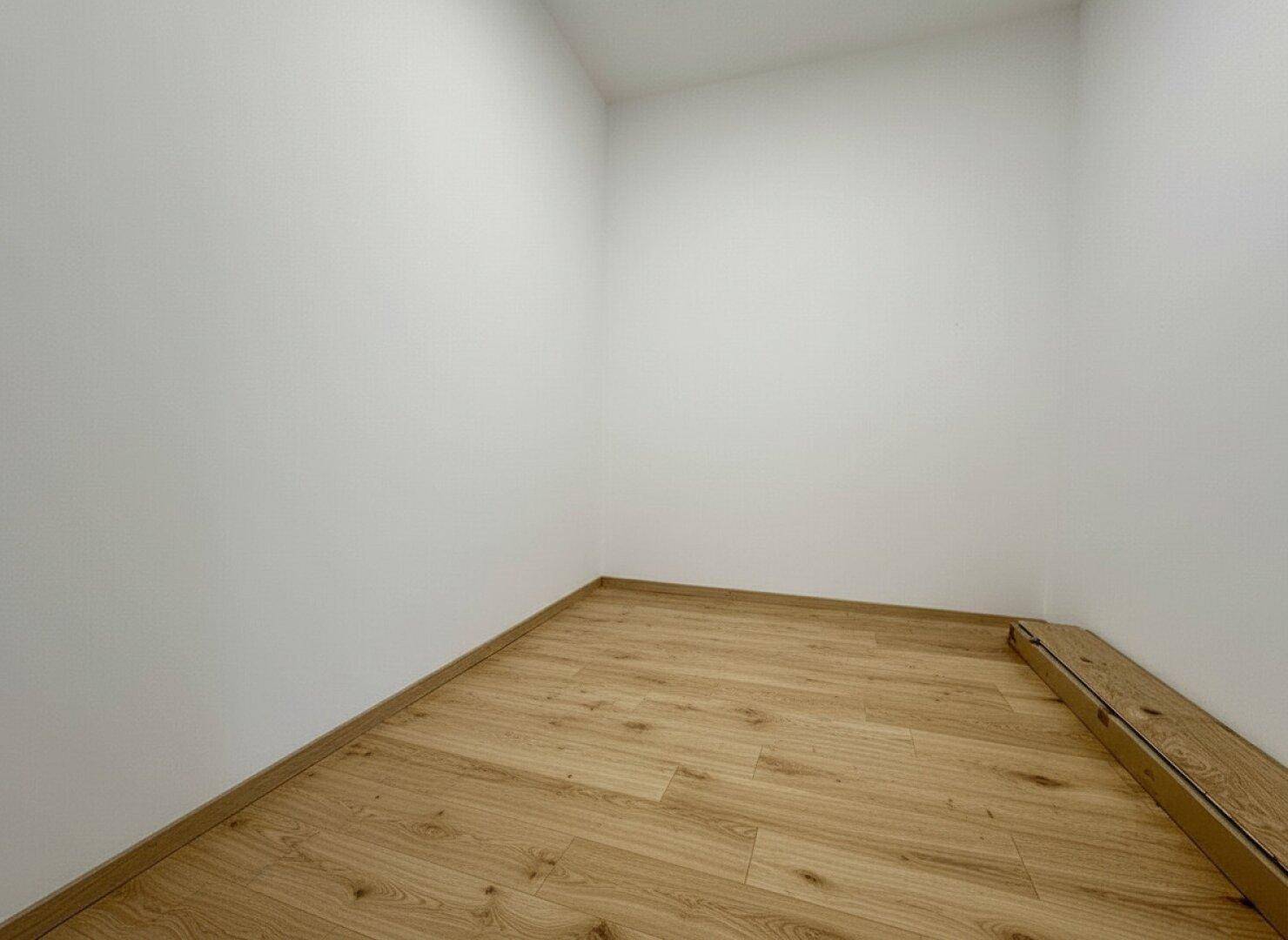 Kleiner, heller Raum mit Holzboden, ideal als Abstellraum oder begehbarer Kleiderschrank.