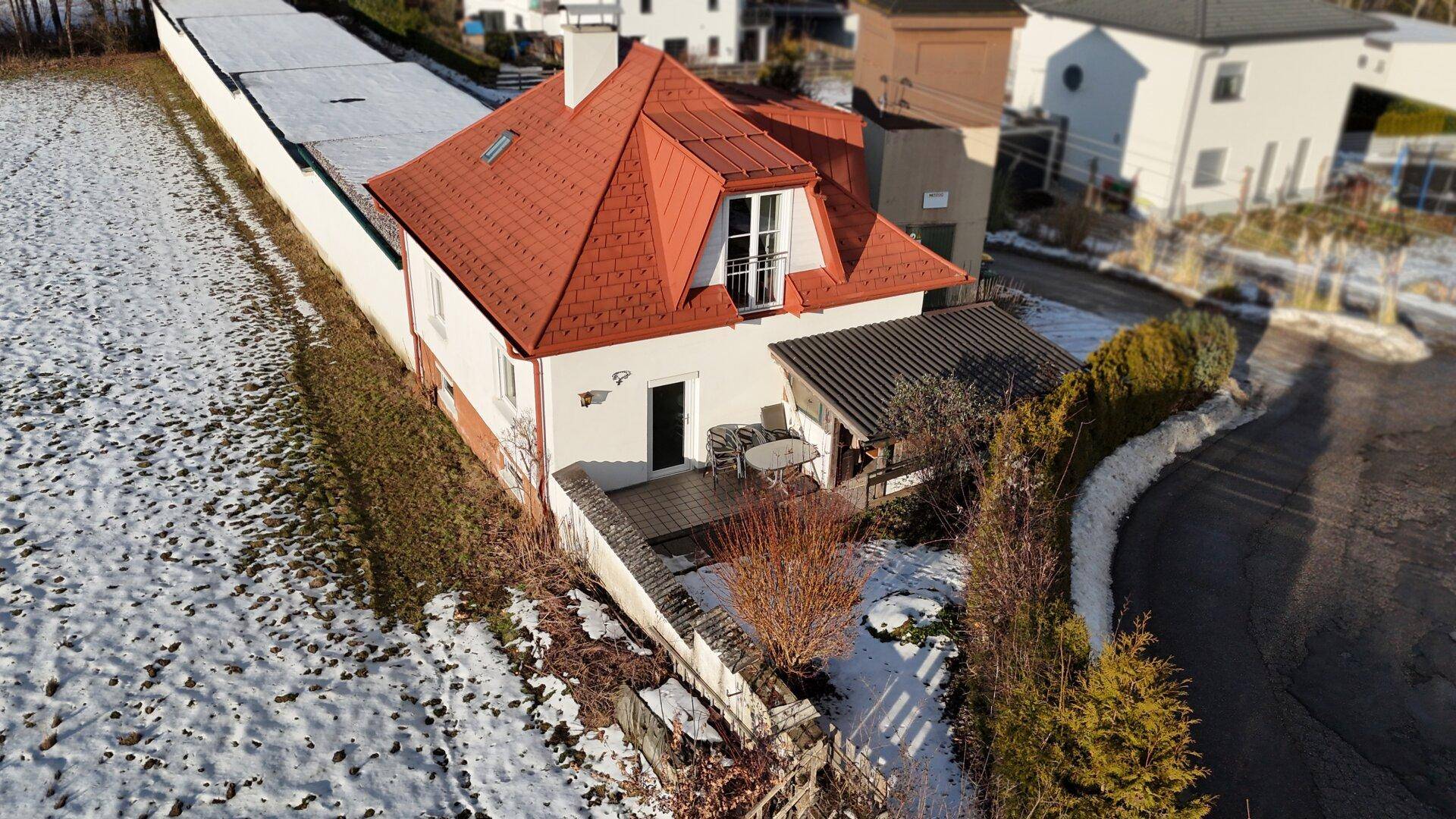 Rückansicht des Hauses mit kleiner Terrasse und Blick auf die verschneite Landschaft.