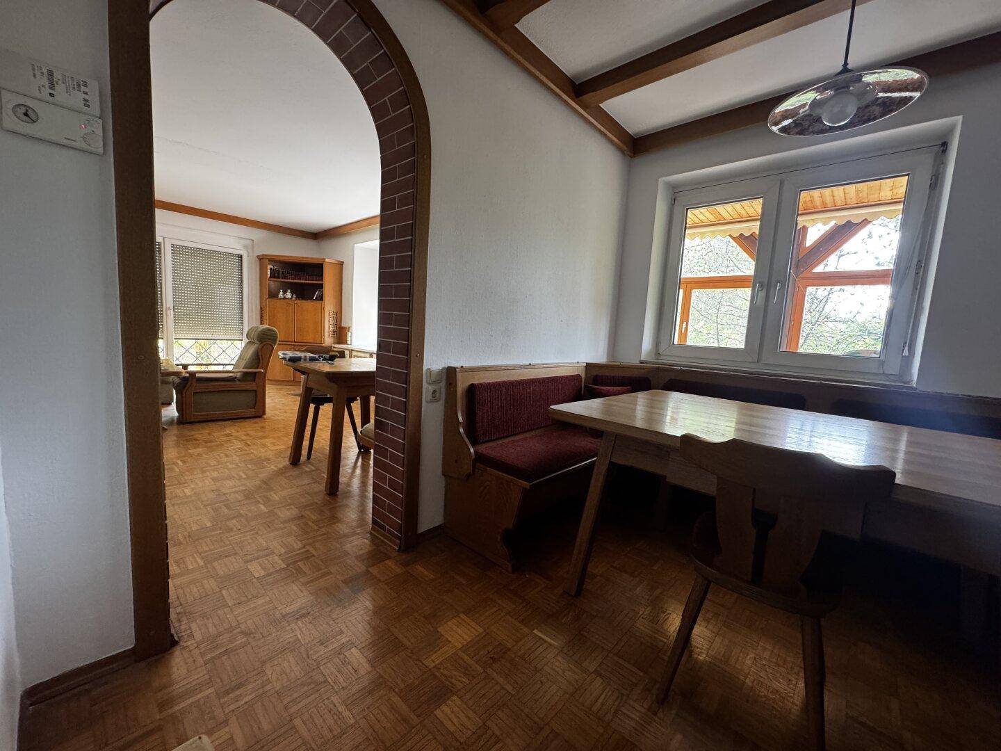 Gemütlicher Essbereich mit Holztisch, Eckbank und Parkettboden, angrenzend an Wohnzimmer.