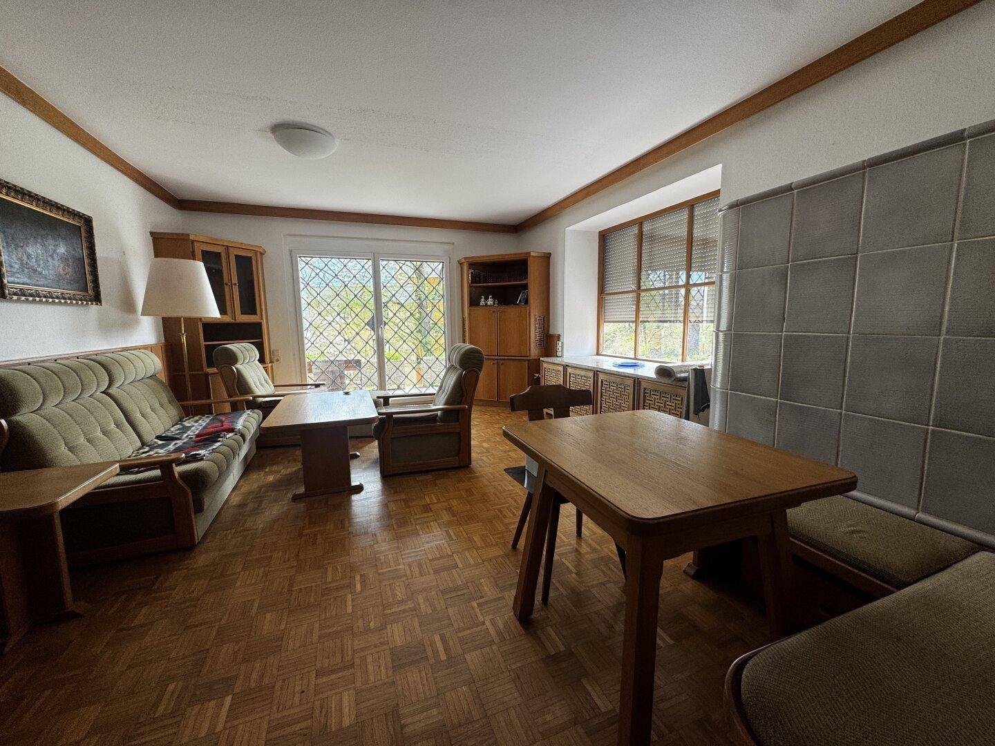 Geräumiges Wohnzimmer mit Parkettboden, traditionellen Möbeln und Kachelofen.