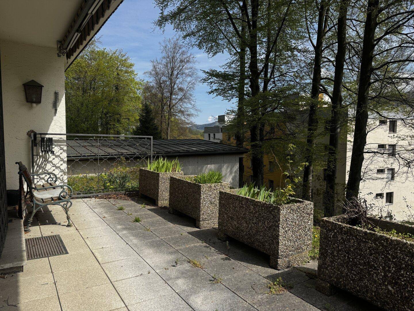 Terrasse mit Steinplatten und Pflanzkübeln, bietet einen Sitzbereich im Freien.