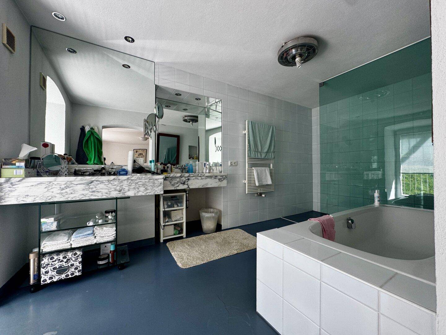 Geräumiges Badezimmer mit Doppelwaschbecken, großer Spiegelfläche und Badewanne, modern gefliest.