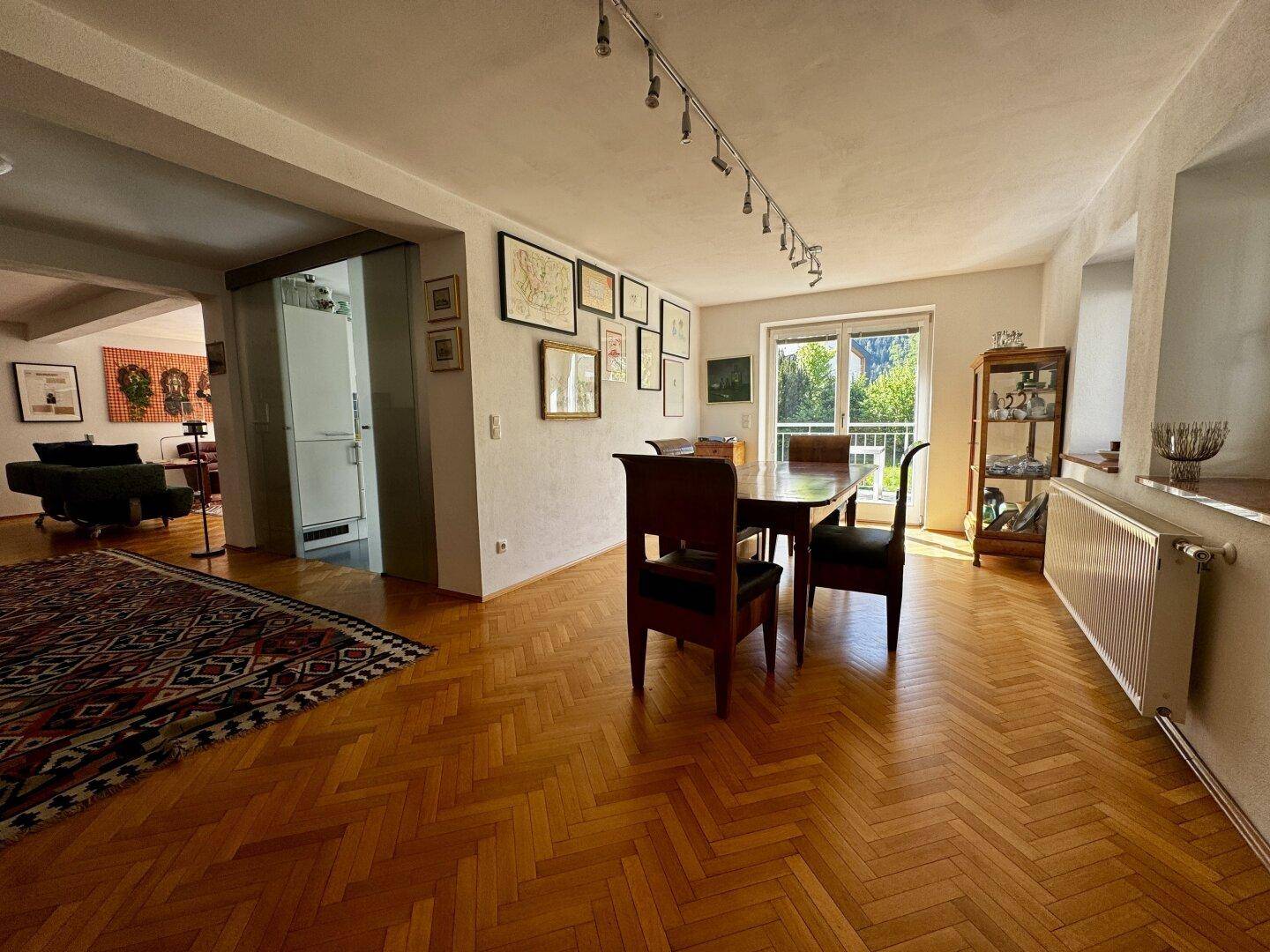 Geräumiger Essbereich mit Holztisch, Parkettboden und großen Fenstern mit Grünblick.