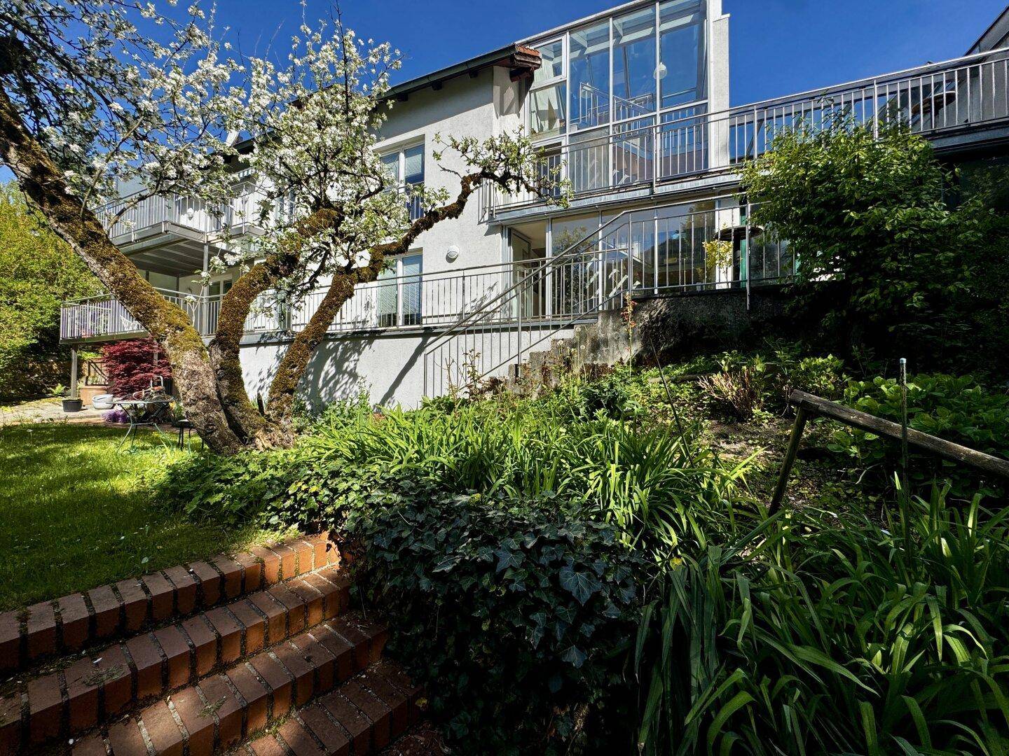 Ansicht des Hauses vom Garten aus mit Treppen und üppiger Bepflanzung.