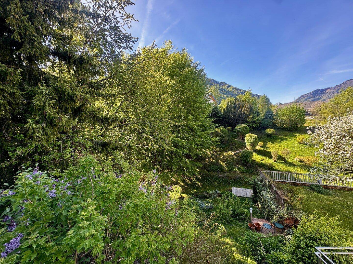 Malerischer Blick auf eine grüne Hügellandschaft mit Bäumen und einem Gebäude in der Ferne.