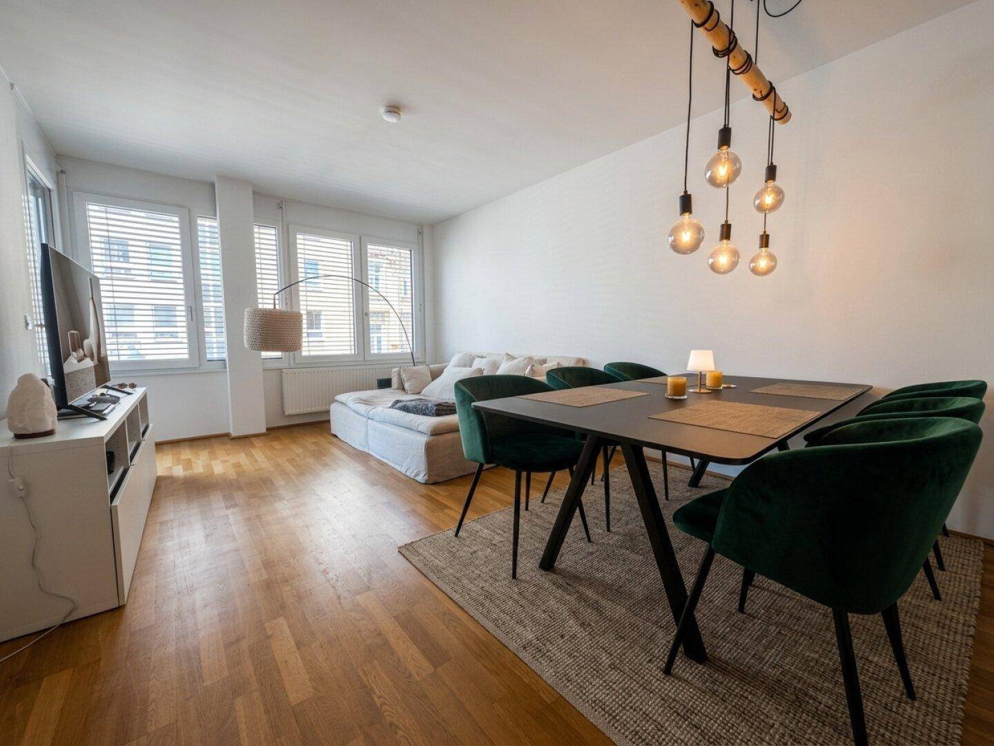 Gemütlicher Wohn- und Essbereich mit Holzboden, modernem Esstisch und Sofa.