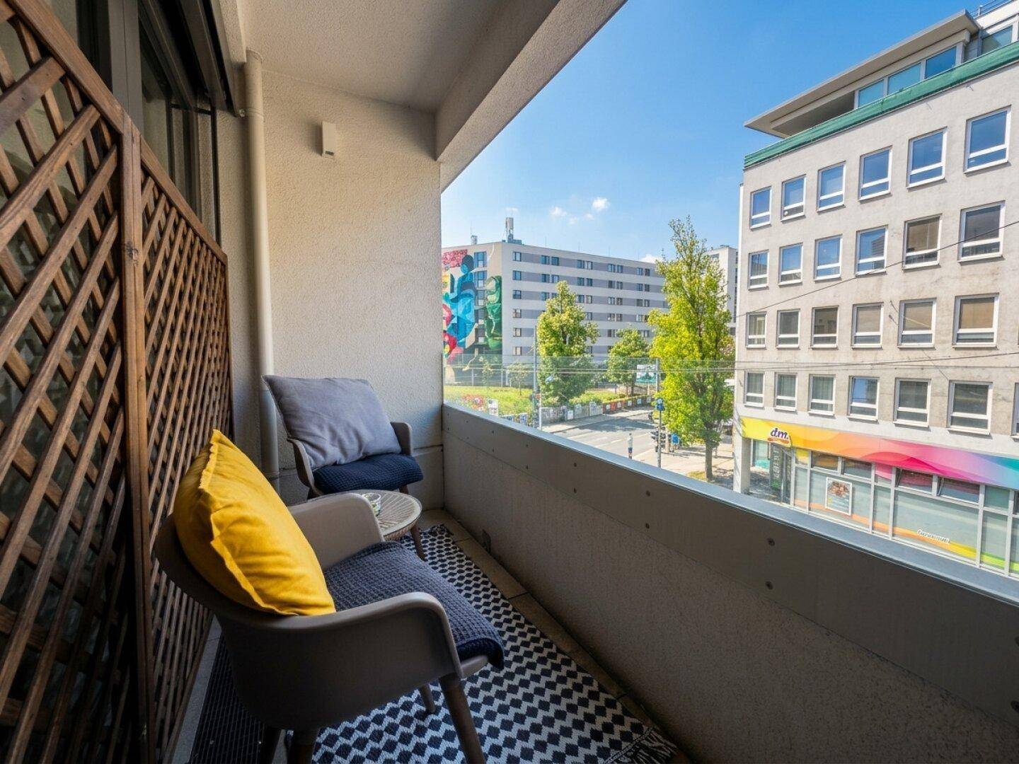 Kleiner Balkon mit Sitzgelegenheiten und Blick auf die Stadtstraße.