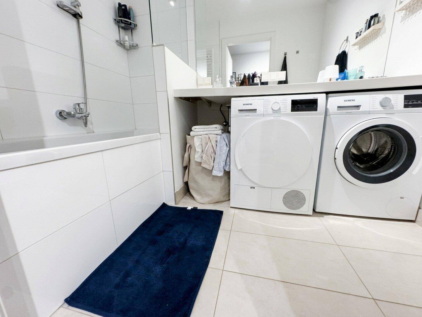 Modernes Badezimmer mit Badewanne, Waschmaschine und Trockner.