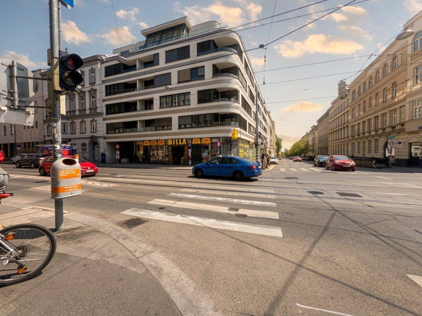 Modernes Wohngebäude an einer belebten Stadtstraße mit Geschäften im Erdgeschoss.