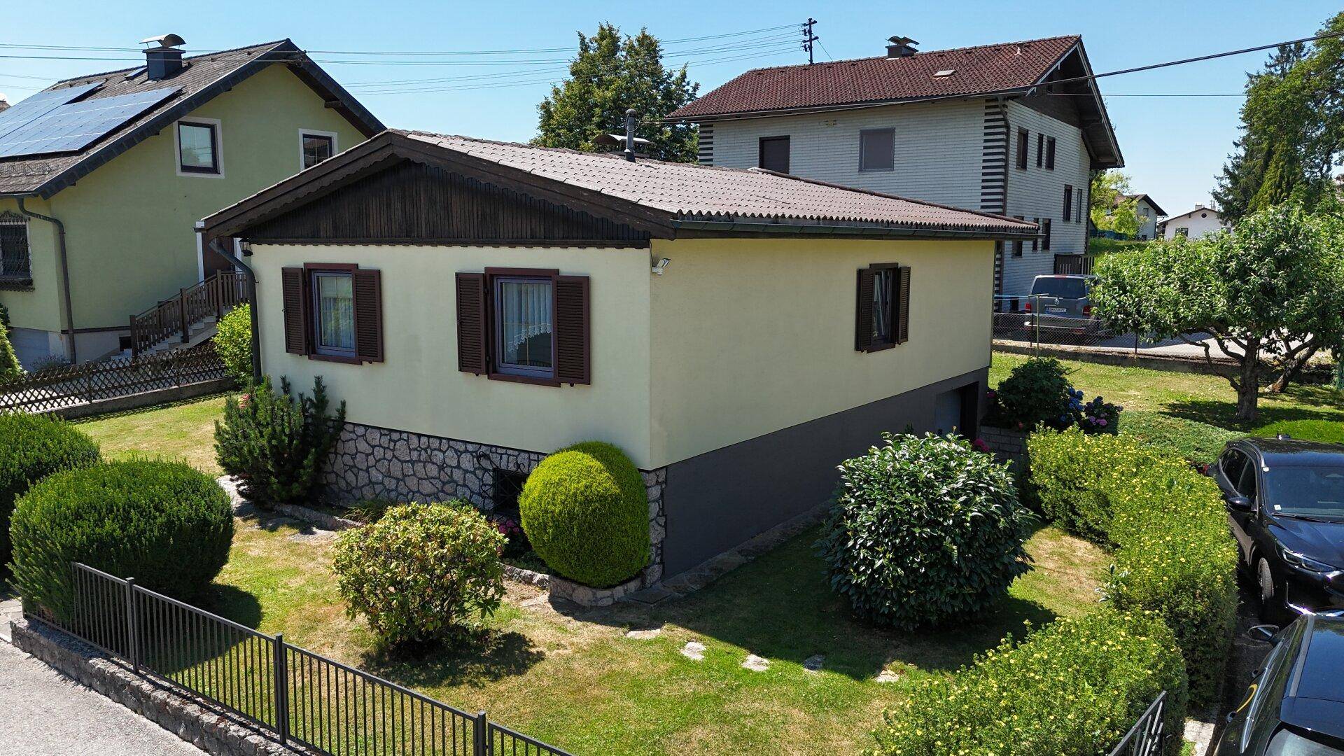 Seitenansicht des Hauses mit gepflegtem Gartenbereich und angrenzender Straße.