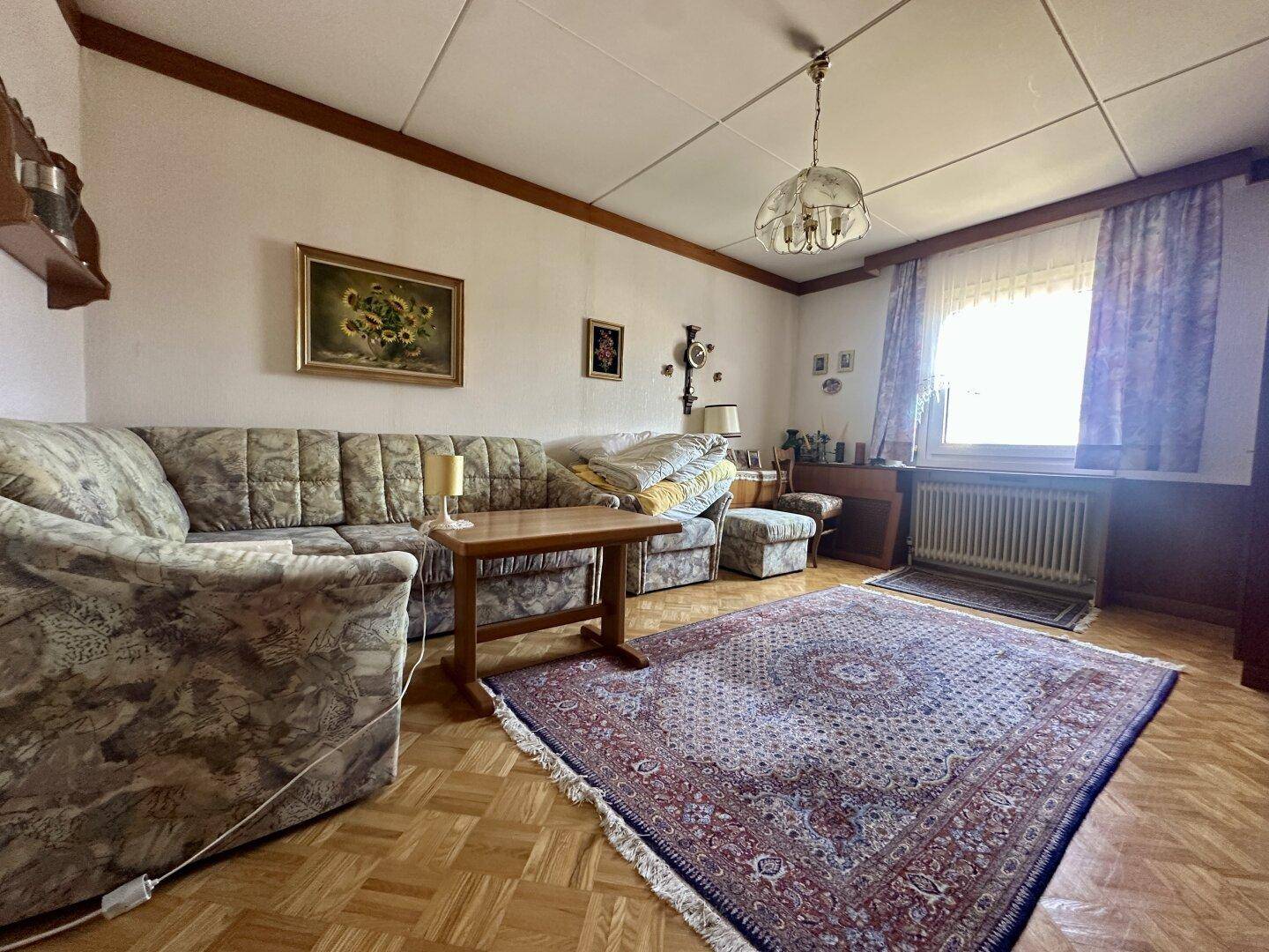 Traditionelles Wohnzimmer mit gemustertem Sofa, Teppich und Holzparkettboden.