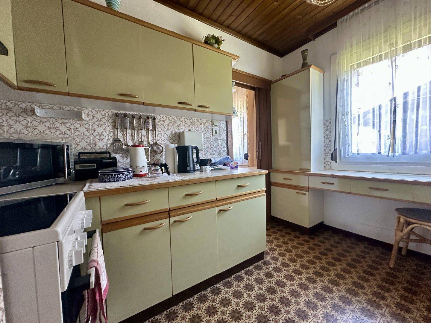 Helle Küche mit Arbeitsplatte, Spüle und Blick durch das Fenster.