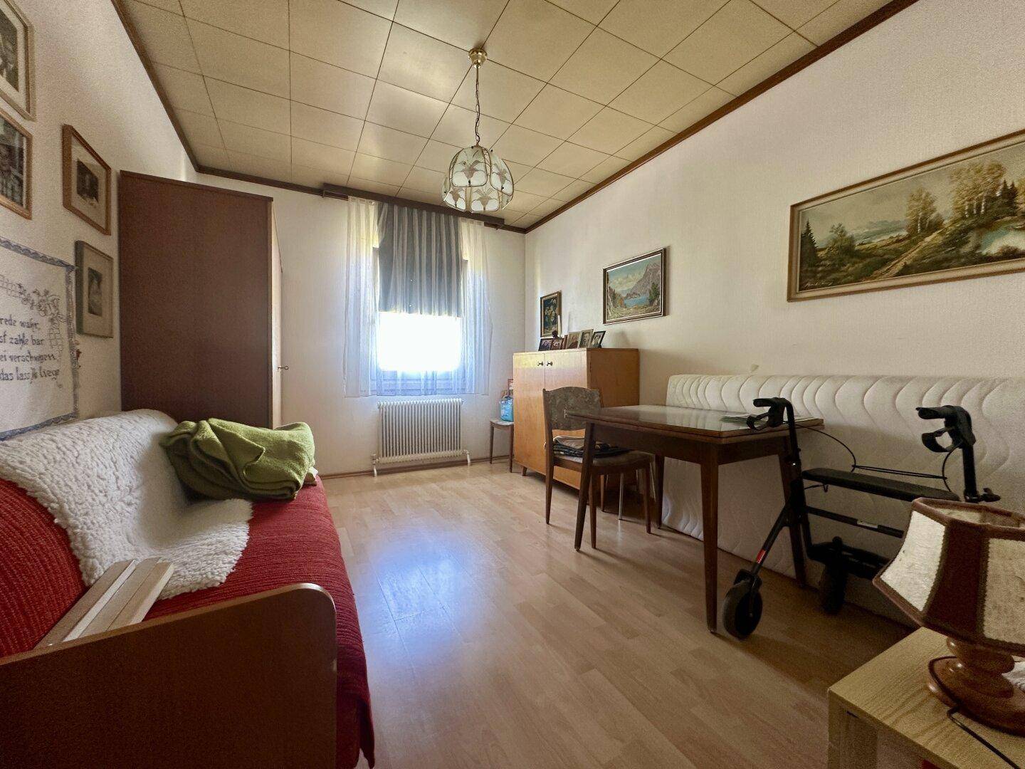 Helles Zimmer mit Holzboden, Schreibtisch und Tagesbett.
