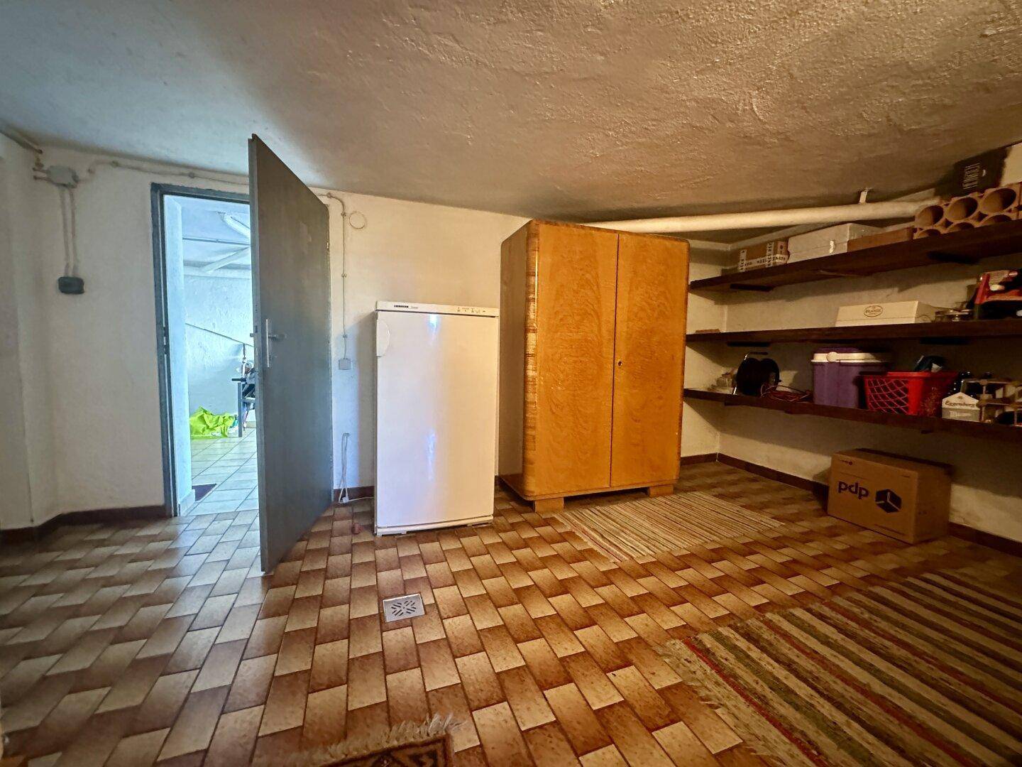 Kellerraum mit Fliesenboden, Schränken und Regalen für Lagerung.