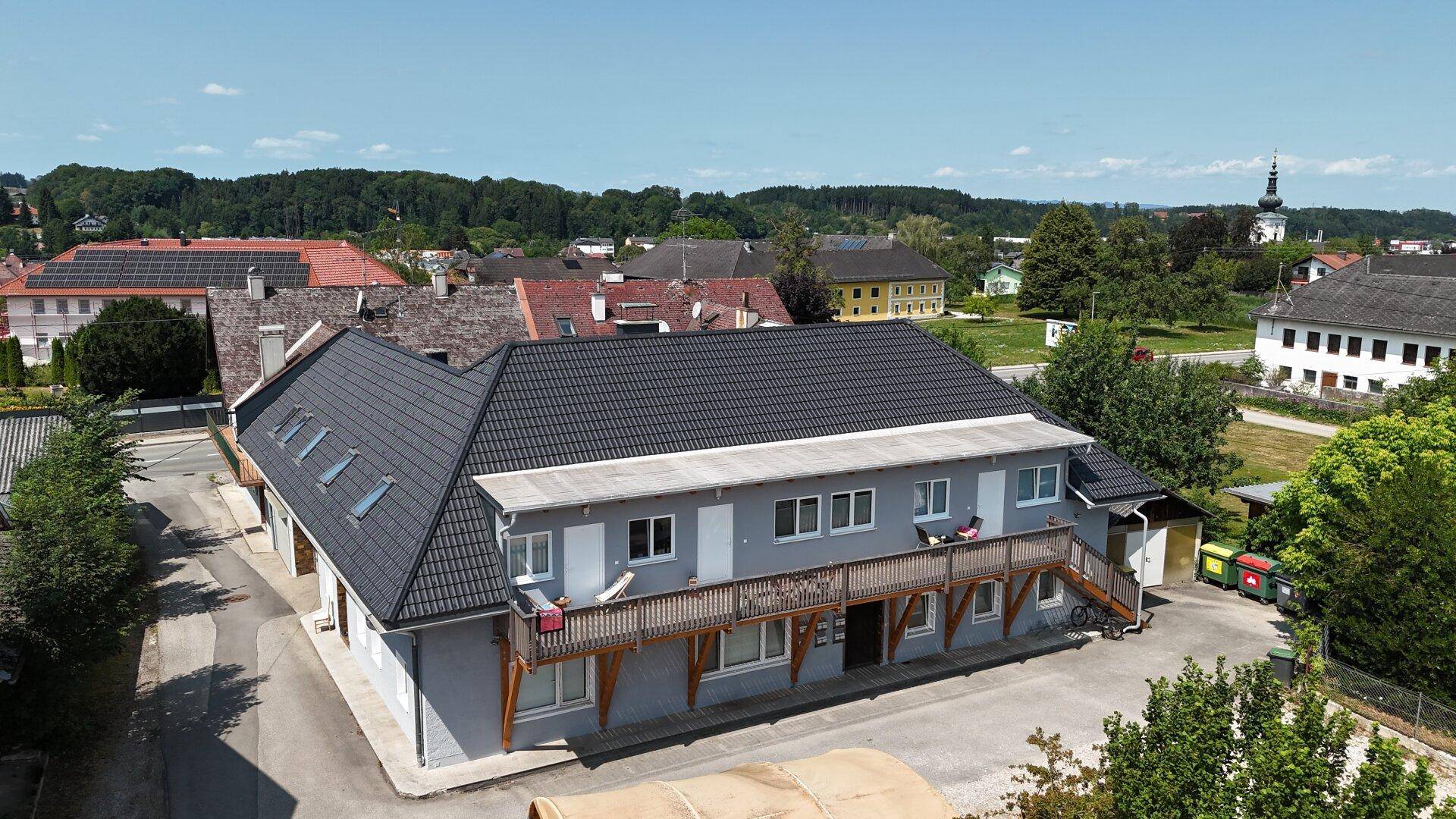 Weitläufige Luftaufnahme des Gebäudes mit Holzbalkon und Blick auf die umliegende ländliche Bebauung.