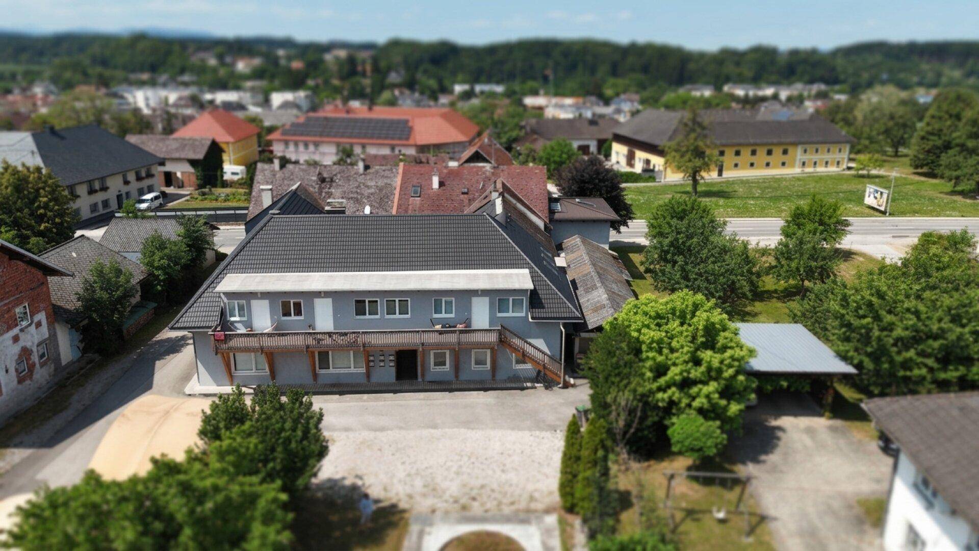 Weitläufige Luftaufnahme des Hauptgebäudes mit Holzbalkon und dem gepflegten Außenbereich mit Rasenfläche.