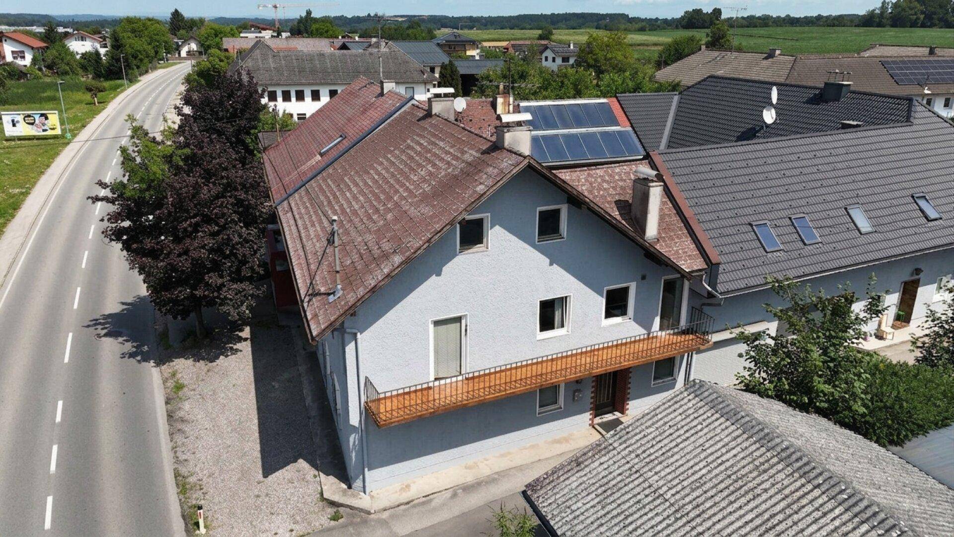 Luftaufnahme des Gebäudes mit rotem Ziegeldach und schmalem Balkon, angrenzend an eine Landstraße.