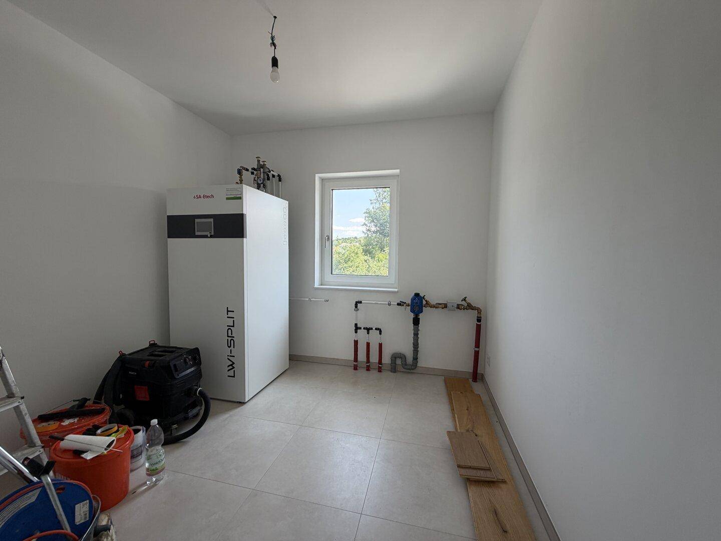 Hauswirtschaftsraum mit moderner Wärmepumpe und Fenster, ideal für technische Installationen.