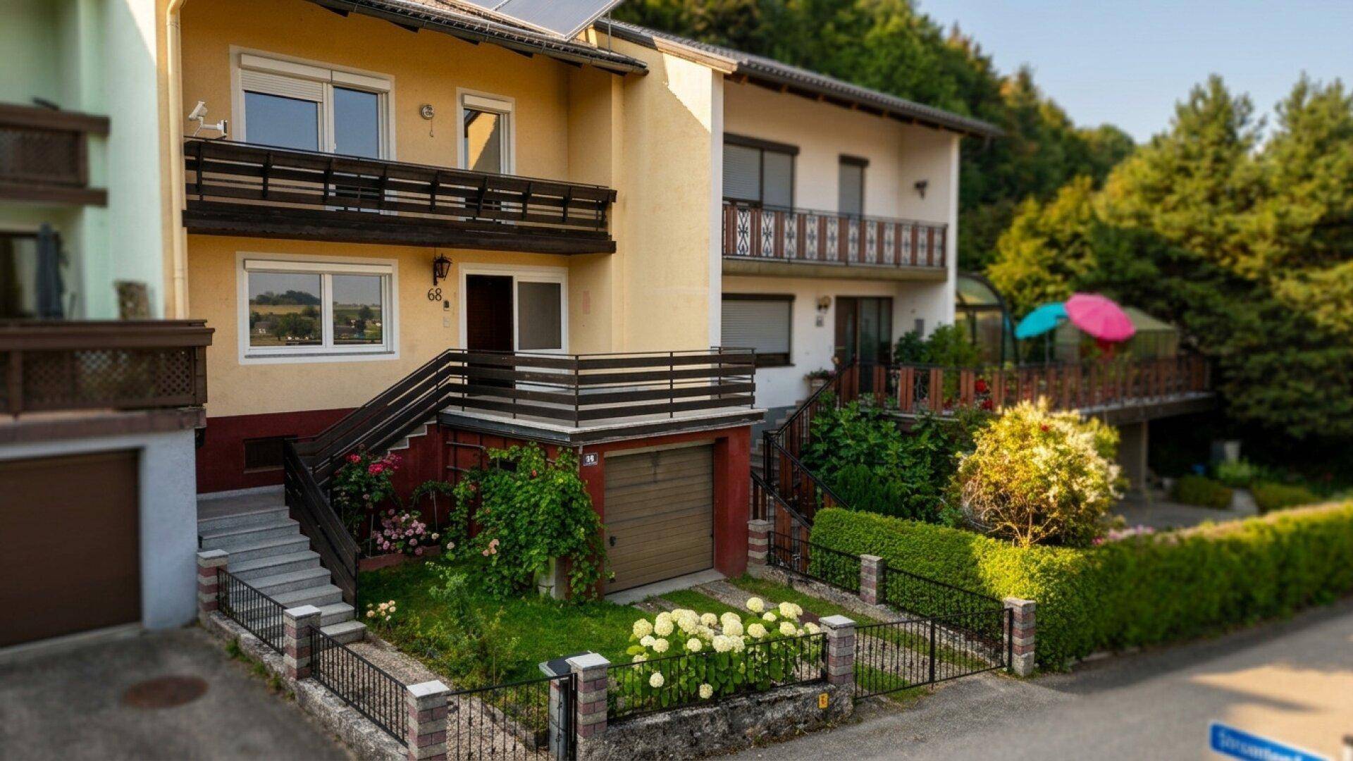 Reihenhausfassade mit Balkonen, Garagen und gepflegten Vorgärten an einem sonnigen Tag.