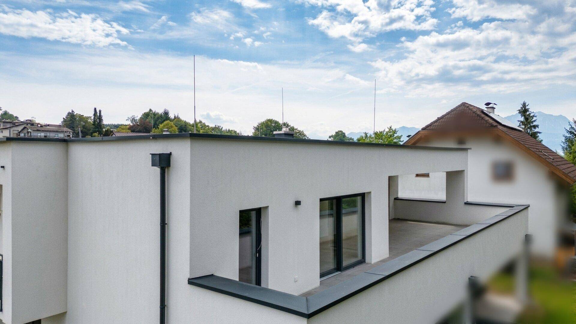 Teilansicht des Gebäudes mit einer geräumigen Terrasse und Blick auf die umliegende Landschaft.