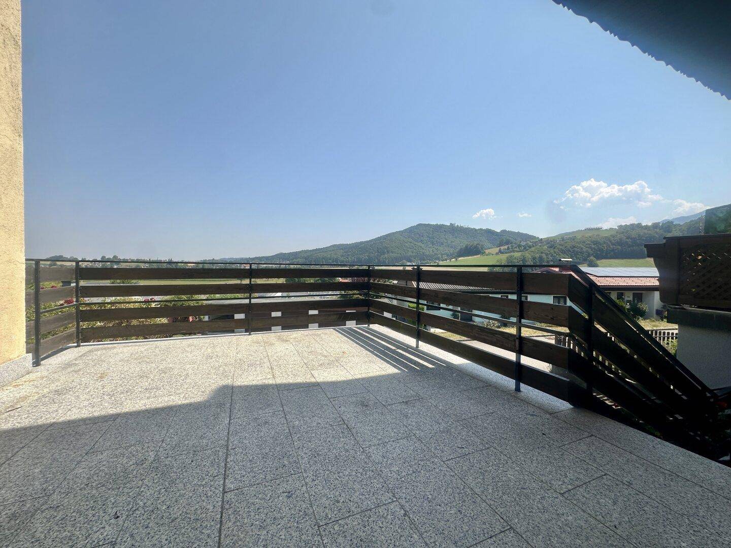Große Terrasse mit Fliesenboden und weitem Blick auf die umliegende Hügellandschaft.