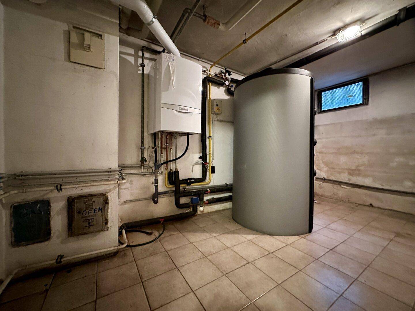Heizungsraum im Keller mit moderner Heizungsanlage und Warmwasserspeicher.