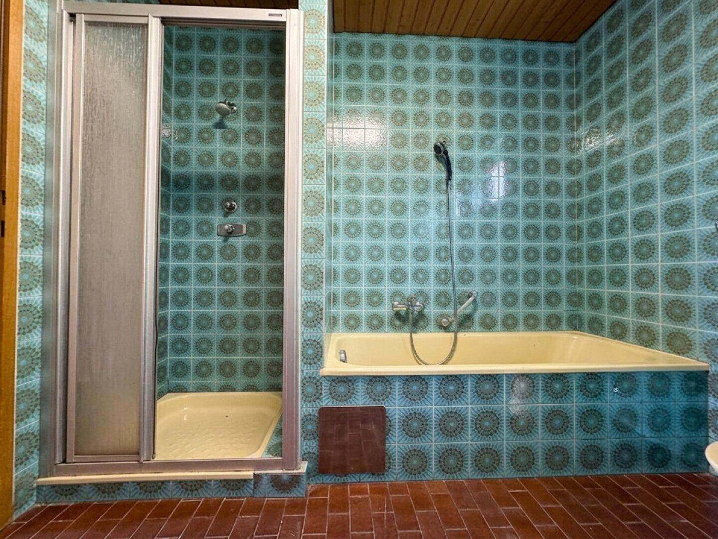 Badezimmer mit blauen Retro-Fliesen, Badewanne und separater Duschkabine.