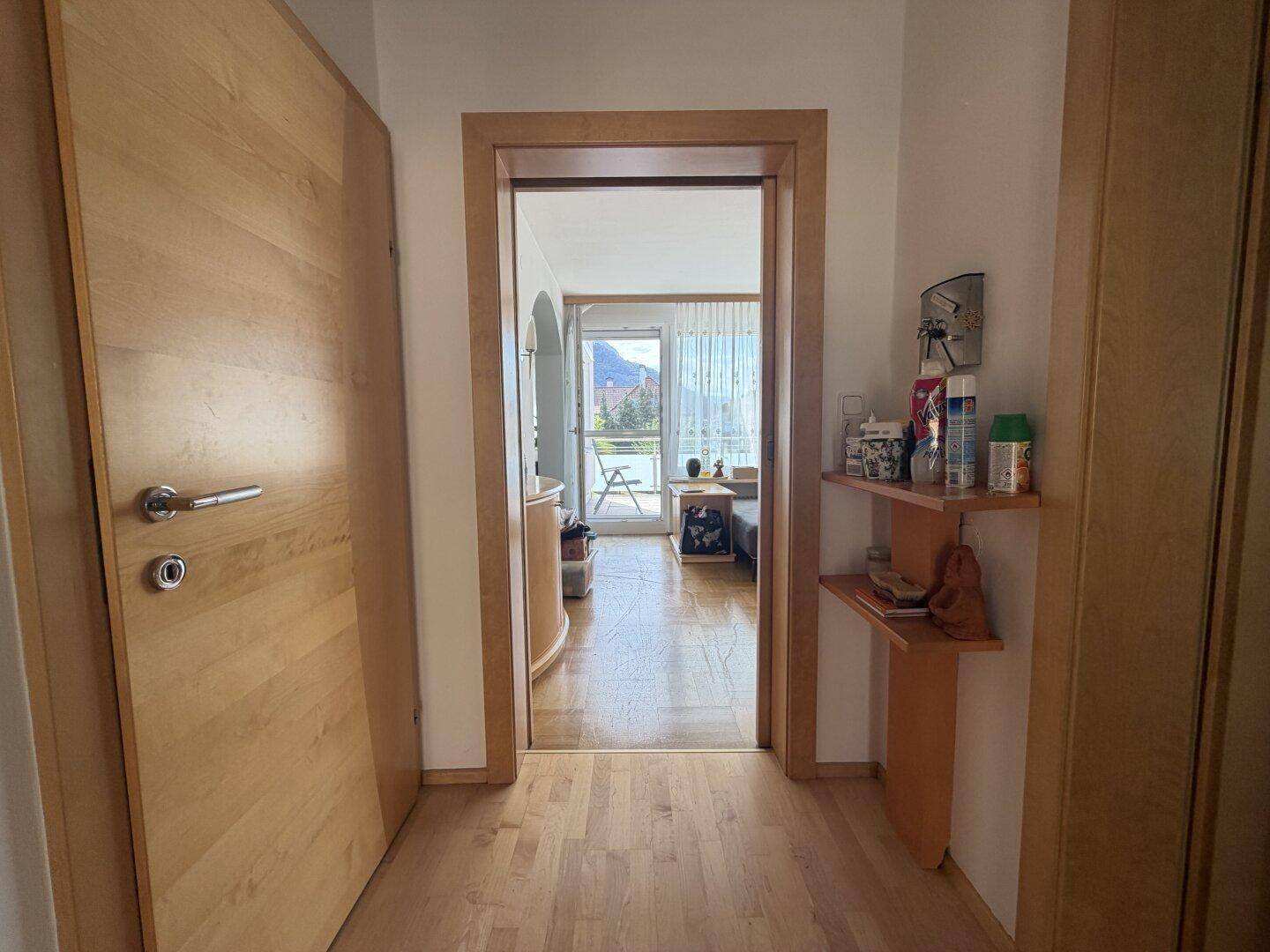Heller Flur mit Holztüren und Blick in einen angrenzenden Raum mit Balkonzugang.