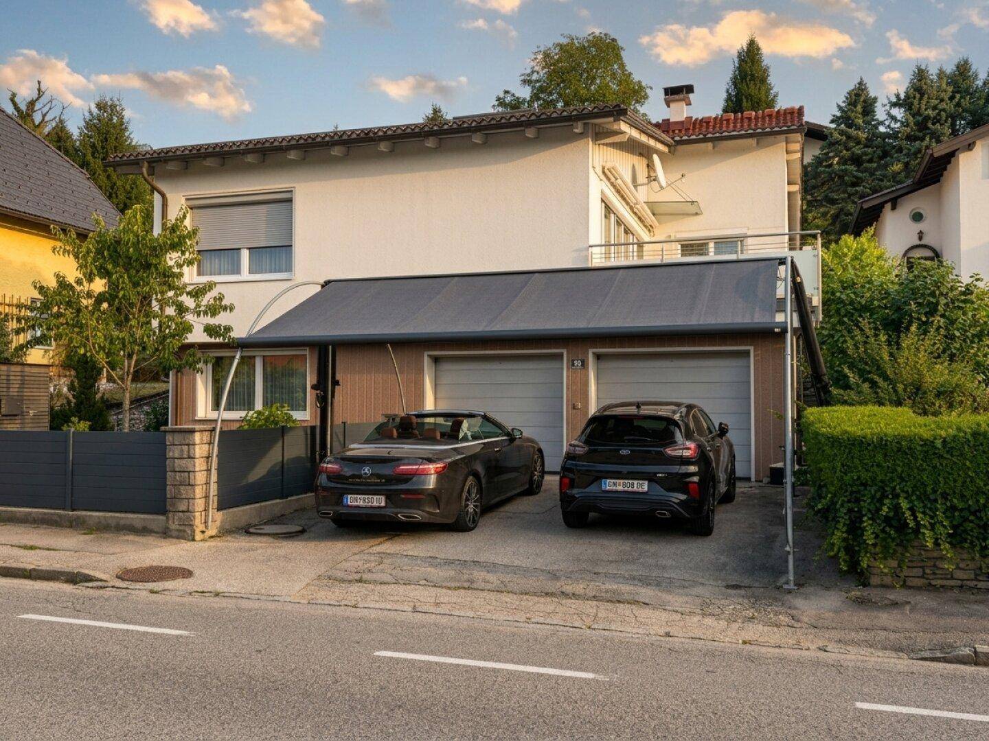 Ansicht des Hauses mit Doppelgarage und überdachtem Stellplatz für zwei Fahrzeuge.