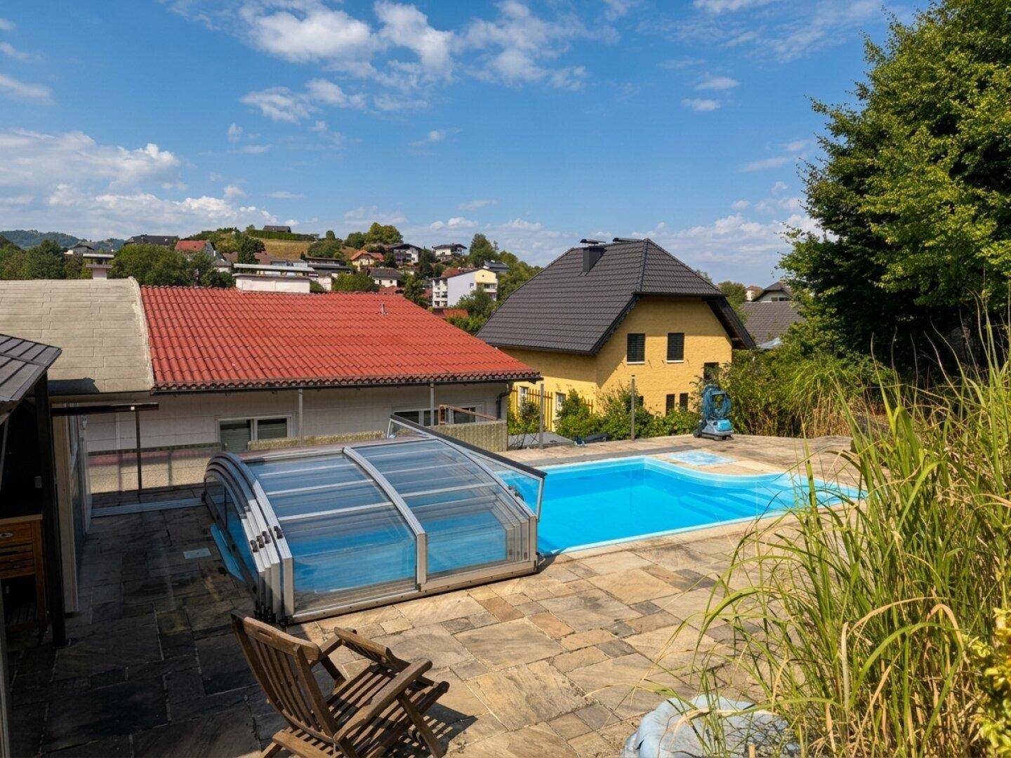 Poolbereich mit Abdeckung, Liegestühlen und Blick auf die umliegende Wohngegend.
