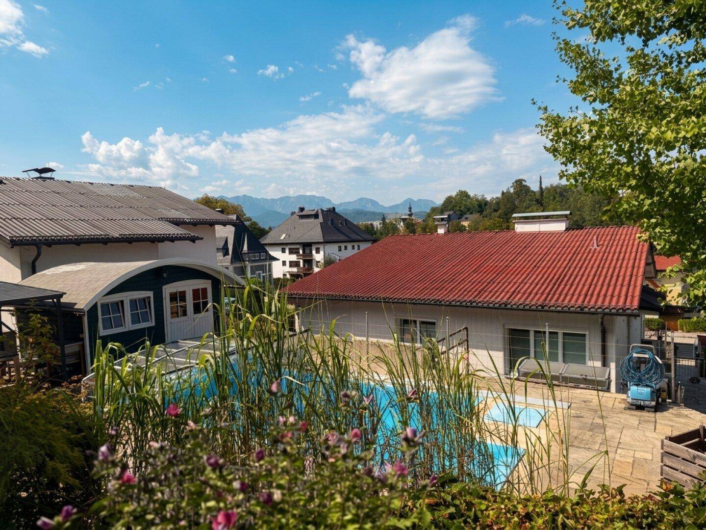 Außenbereich mit Swimmingpool, gepflasterter Terrasse und Bergblick im Hintergrund.