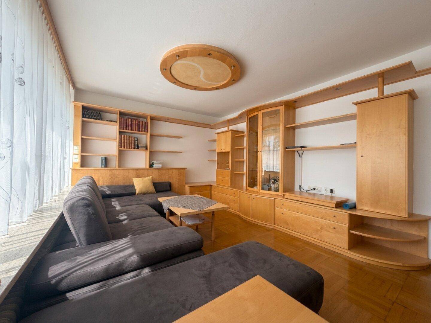 Gemütliches Wohnzimmer mit großem Ecksofa, maßgefertigten Holzregalen und warmer Beleuchtung.