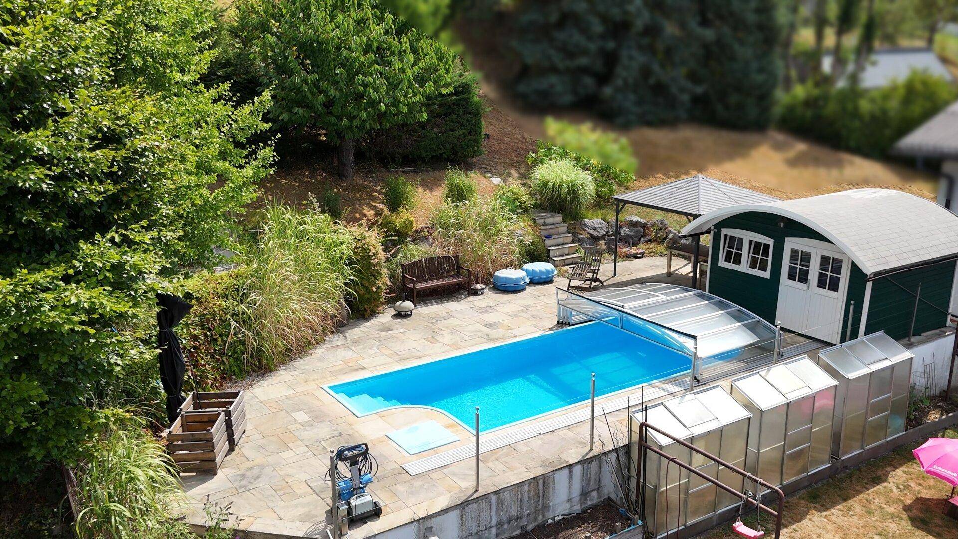 Gartenbereich mit großem Pool, umgeben von üppigem Grün und einem kleinen Gartenhaus.