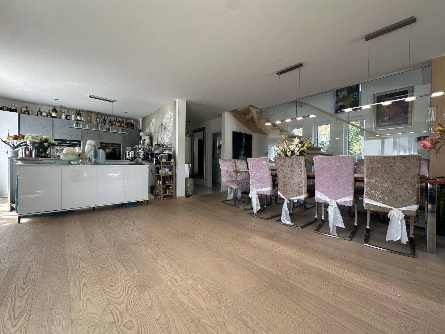 Geräumiger offener Wohn-Essbereich mit Holzboden, moderner Küche und eleganten Esszimmerstühlen.