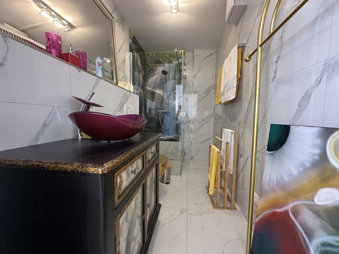 Modernes Badezimmer mit Marmorfliesen, auffälligem Waschbecken und begehbarer Dusche.