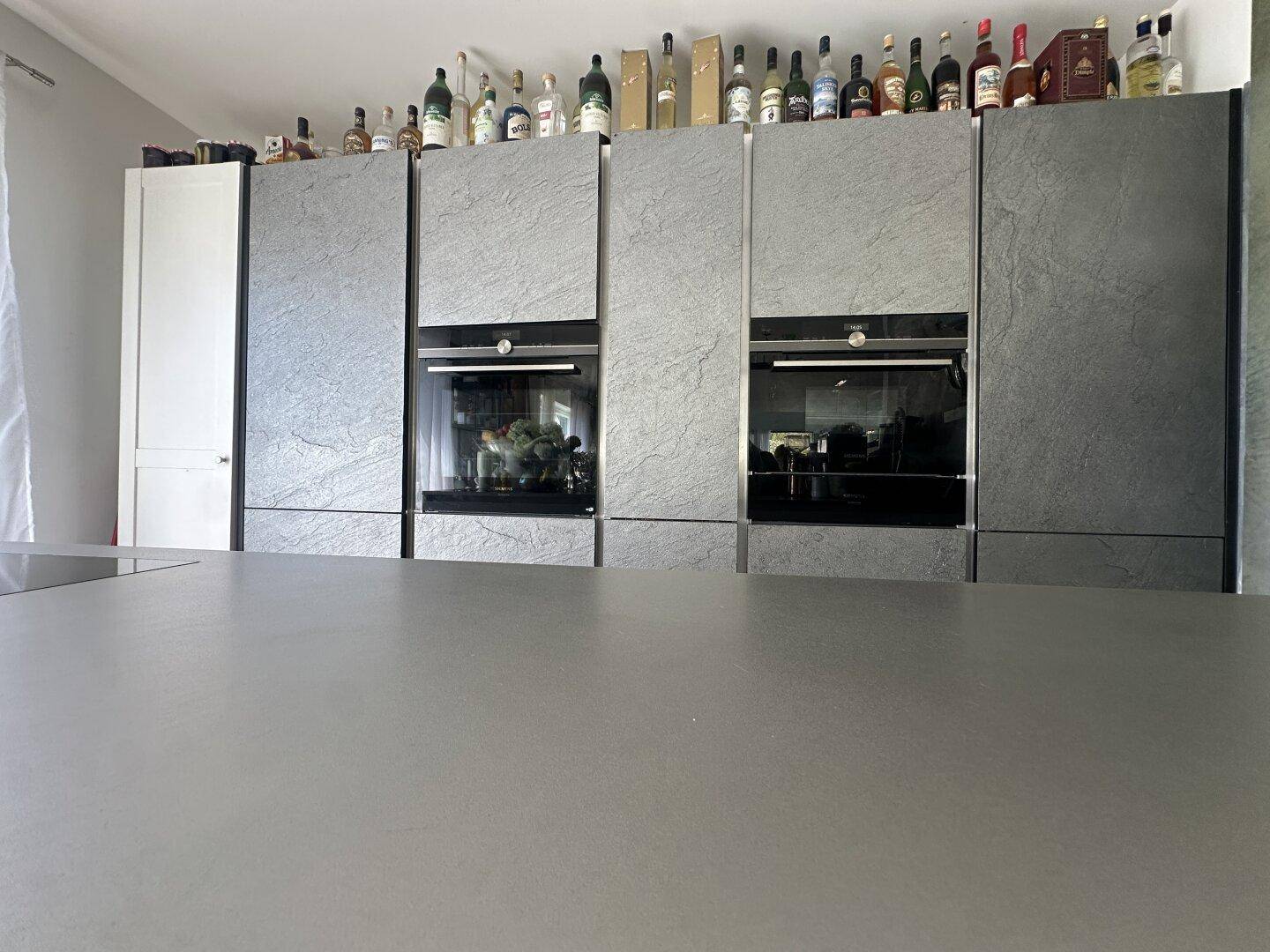 Elegante Küche mit grauen Schieferfronten, integrierten Geräten und einer großen Arbeitsfläche.