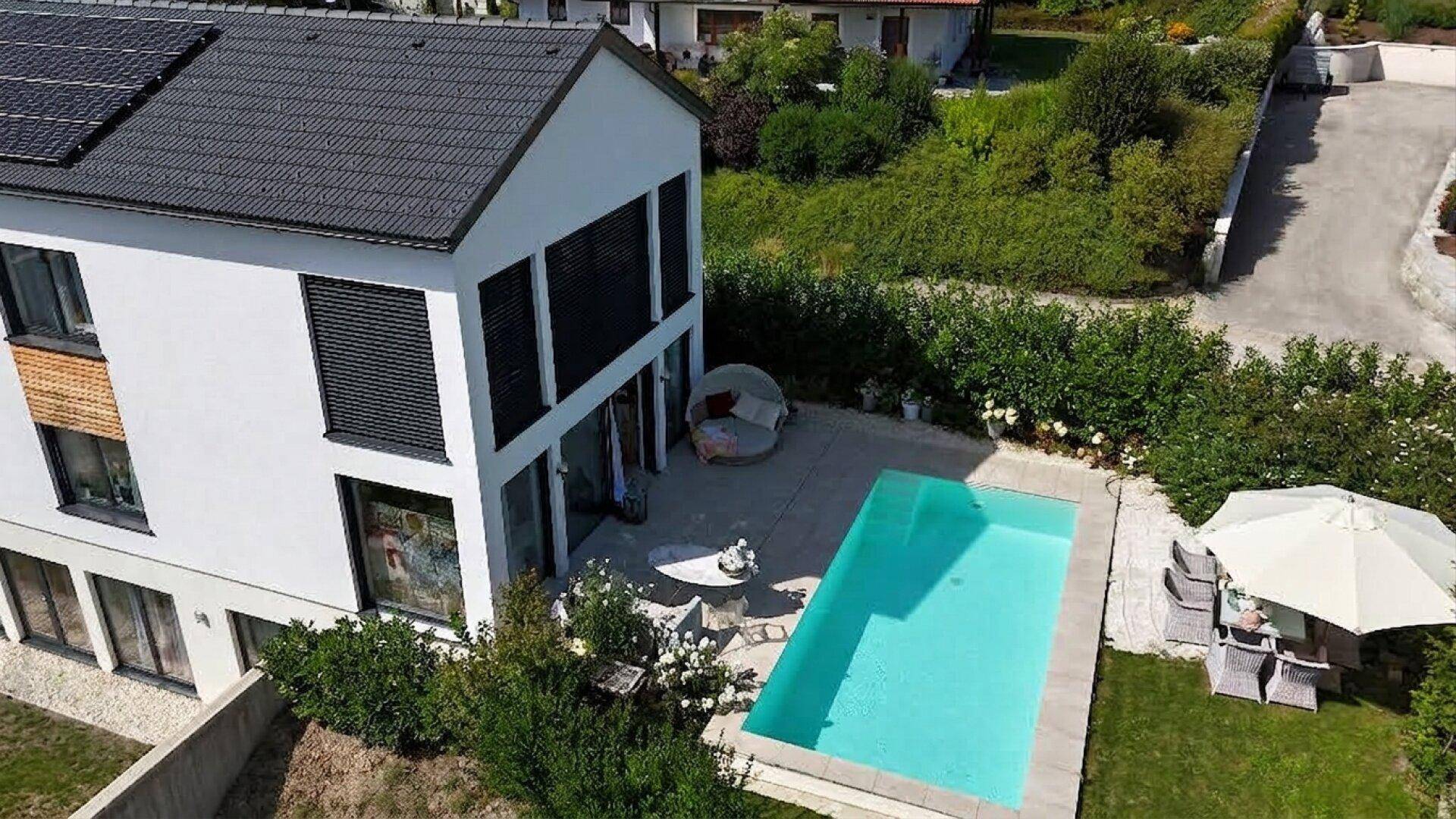 Vogelperspektive auf ein modernes Haus mit Poolbereich, Terrasse und gepflegtem Garten.