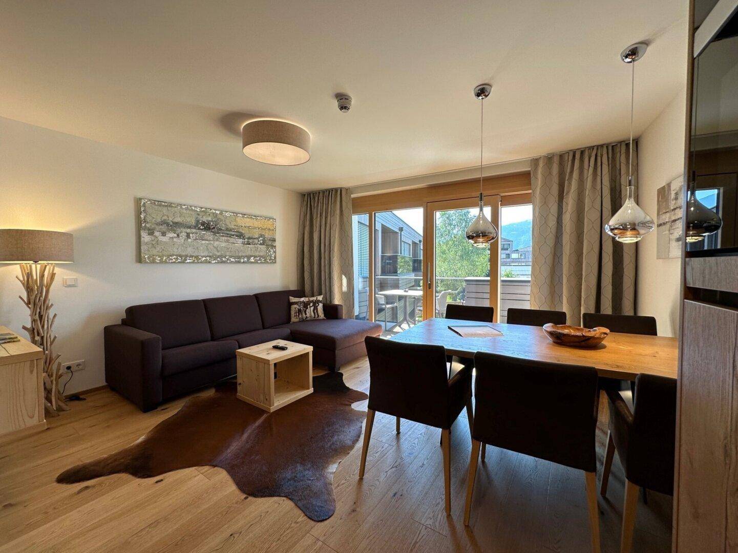Gemütlicher Wohn-Essbereich mit Holzboden, bequemer Couch und direktem Zugang zu einem Balkon.