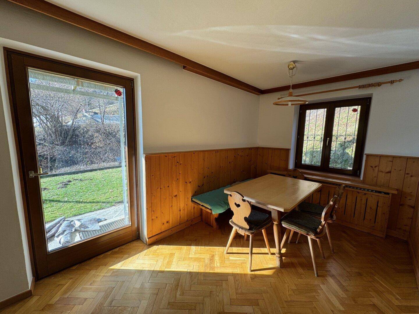 Gemütlicher Essbereich mit Holztäfelung, Parkettboden und direktem Zugang zum Garten.