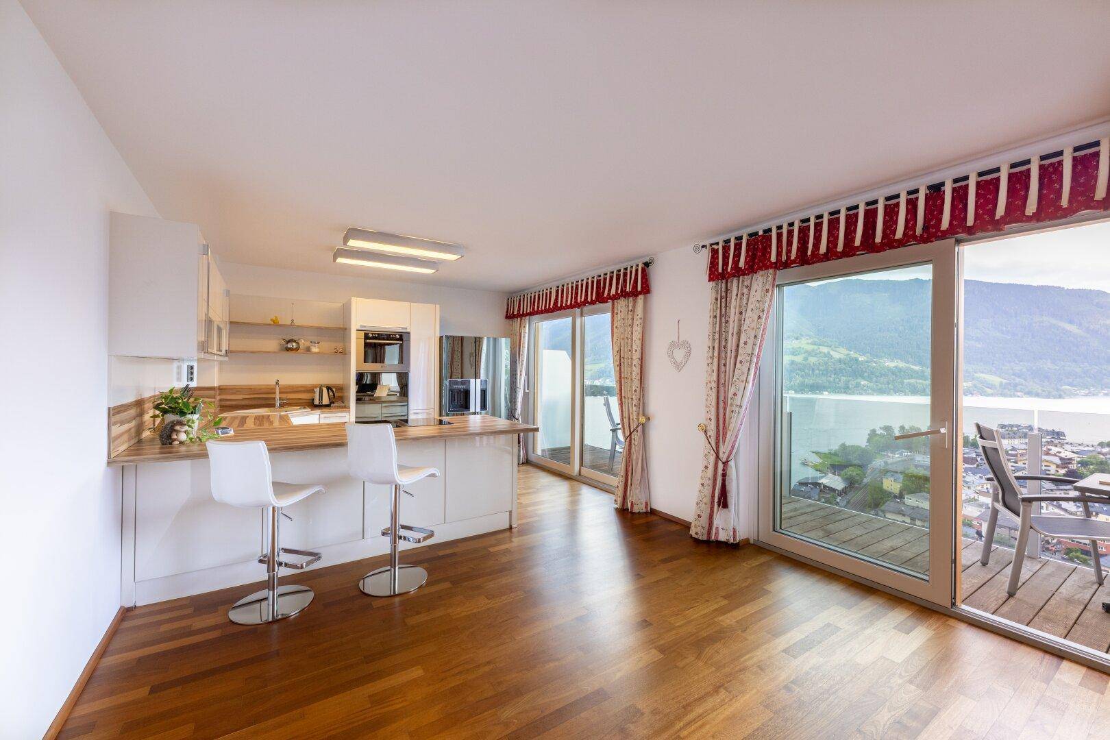 Moderne Küche mit Bartheke, Holzarbeitsplatte und Zugang zu einem Balkon mit Seeblick.