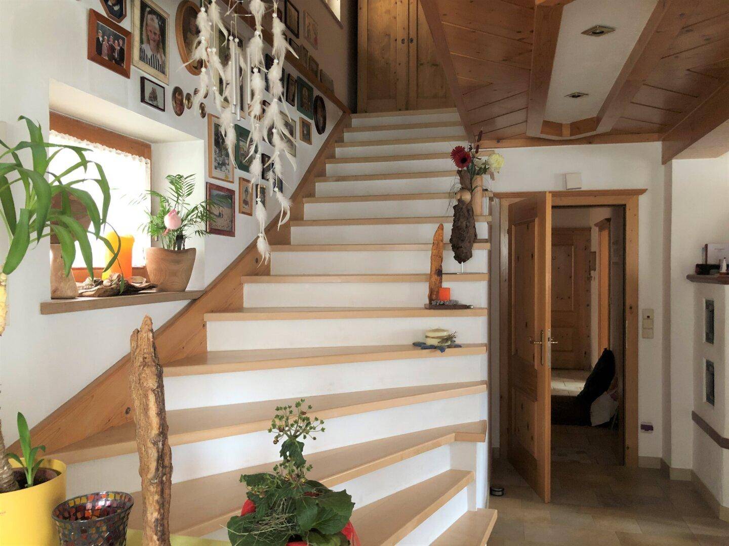 Heller Eingangsbereich mit Holztreppe, weiß gestrichenen Wänden und rustikalen Holzelementen.